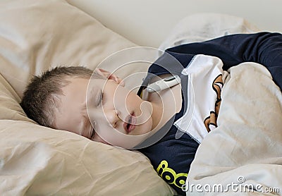 Pre-school sick boy with closed eyes lying in bed with a digital thermometer Stock Photo